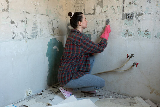 Woman Scraping Old Paint During Home Renovation
