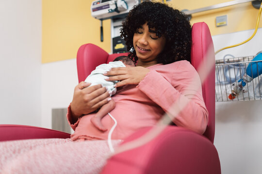 Mother smiling holding newborn baby in hospital room