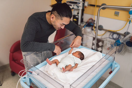 Loving father holding newborn baby's hand in hospital