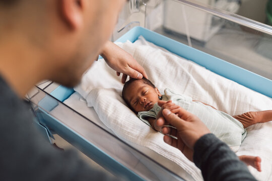 Father holding newborn baby hand at hospital