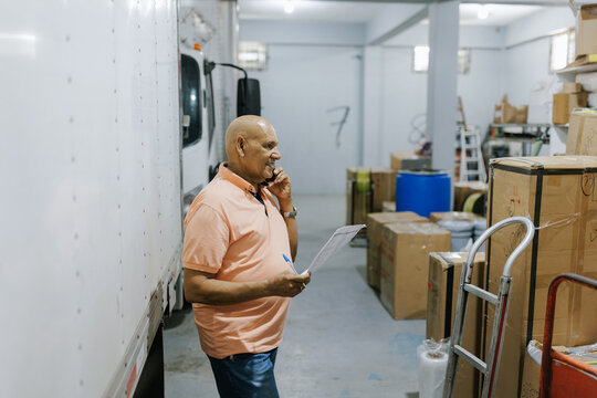 Worker Checks Inventory in Storage Area While Talking on Phone