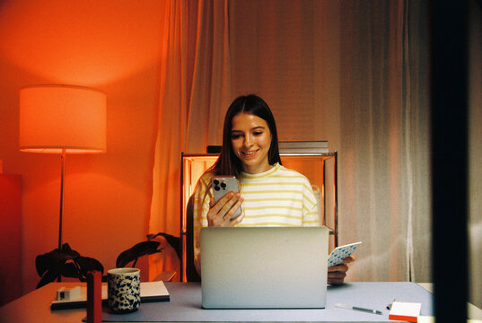Woman using laptop and phone at home film photo