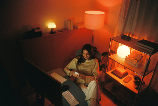Woman Embracing Nighttime at Home with Smartphone, Film Photo