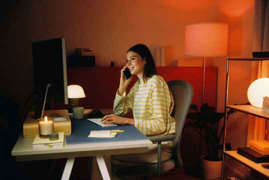 Woman on phone at desk in home office film photo