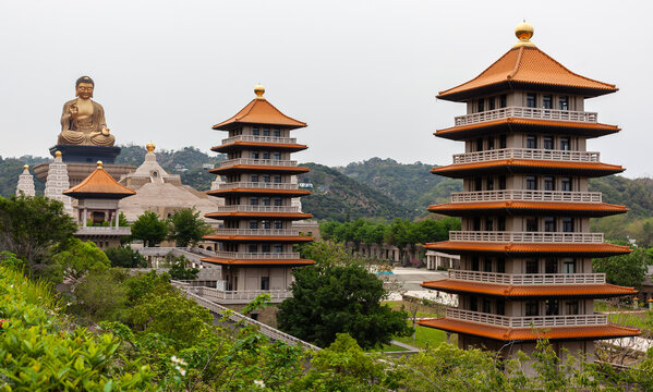 Fo Guang Shan Monastery in Kaohsiung, Taiwan. Grand Buddha statue overlooks traditional pagodas. Historic Buddhist temple complex. Asian religious architecture amid lush greenery.
