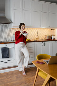 Pregnant woman eating healthy breakfast in modern kitchen