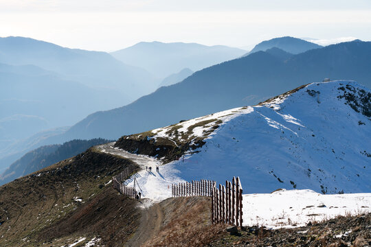 Hikers on snowy mountain ridge with layered blue peaks