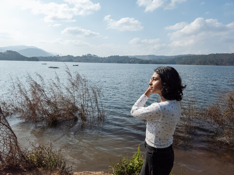 Girl Standing by the Lake During a Clear Day in a Natural Setting