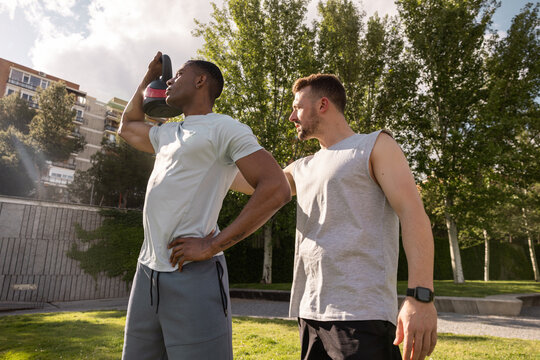 Multiethnic friends exercising with kettlebell outdoors