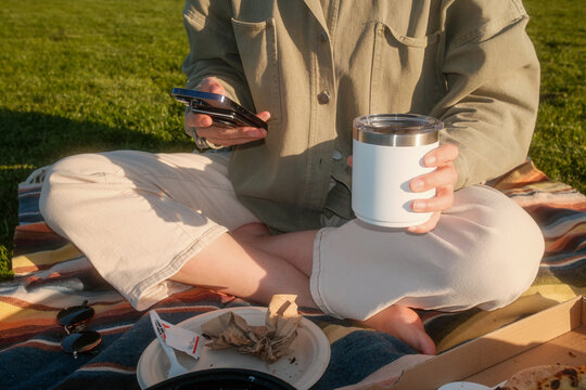 Enjoying Snacks and Drinks While Checking the Phone at the Park