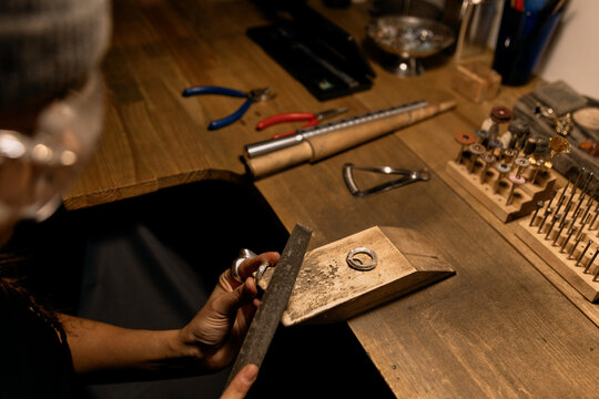 Jeweler is polishing workpiece with hand file
