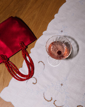 Cherry Cocktail on Delicate Tablecloth with Red Purse