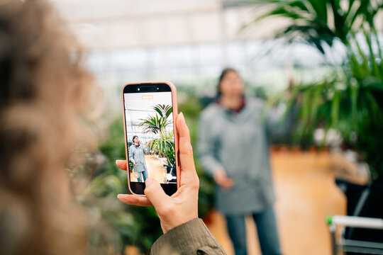 Person Taking a Picture of Friend in Plant Nursery in Daytime