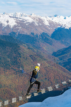 Adventurer crosses suspension bridge over snowy abyss 