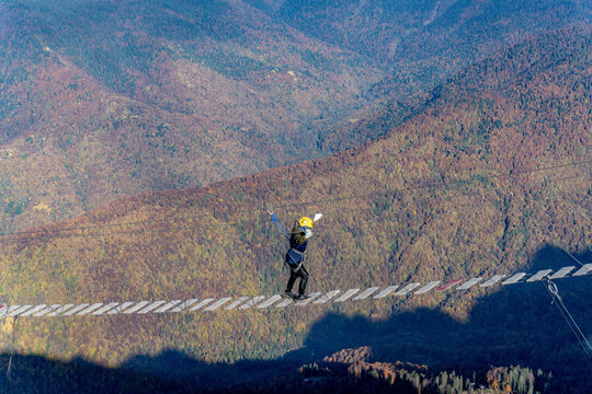 Adventurer crosses suspension bridge over snowy abyss 