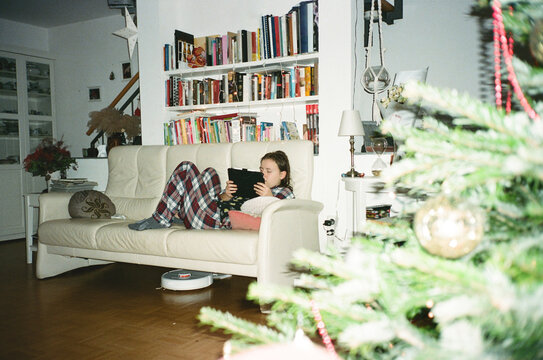 Young woman relaxing on sofa near Christmas tree