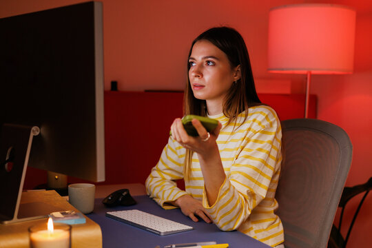 Woman with remote control at desk in evening room