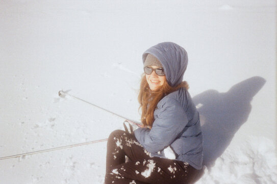 Film Camera Image Of Woman Sitting On Snow Holding Ski Poles 