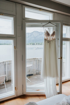 Wedding dress hanging by window overlooking alpine lake