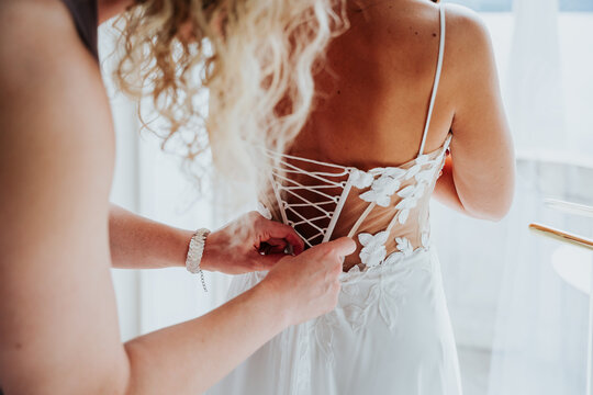 Bride having wedding dress laced before ceremony