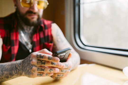 A man using a mobile phone on a train during a trip.