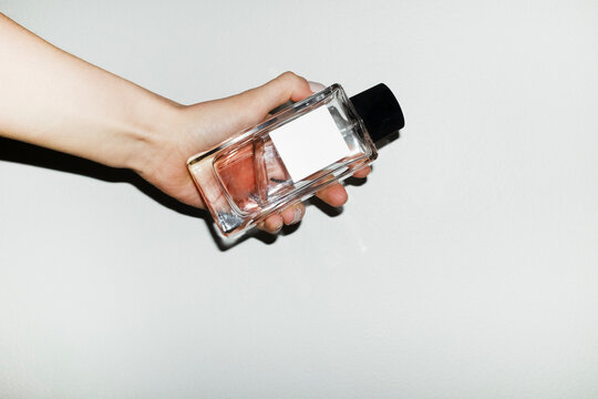 Hand holding classic style mockup perfume bottle with space for text
