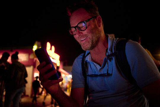 Portrait of a happy man checks his phone in town at night