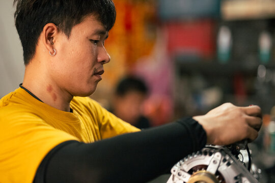 Mechanic repairing engine part in workshop, concentration