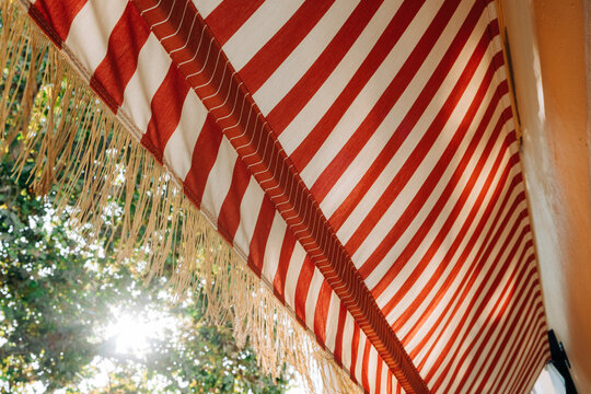 Red and white striped awning with sunlight