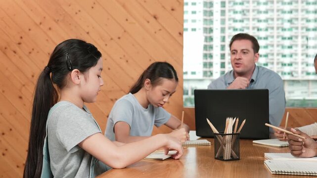 Smart student raised hand to calling happy teacher for checking her work. Skilled teacher looking at high school girl note book and showing a thumb to encourage her at classroom. Creative. Edification