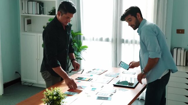 Top down view of caucasian business people talking about UX Ui design while project manager present marketing idea at meeting table with paper and tablet. Diverse team brainstorming idea. Convocation.