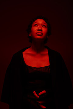 Woman looks up under red lighting in a dark room