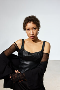 Model poses in black outfit with natural light backdrop in studi
