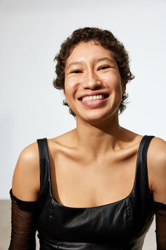 Smiling person wears black dress in bright indoor setting