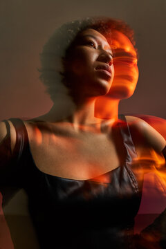 Model poses in studio with layered lighting effects in the backg