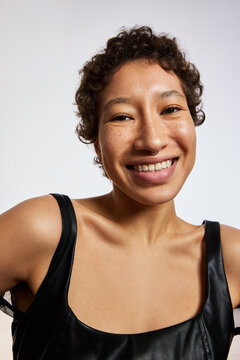 Smiling woman with curly hair showing joy in simple background