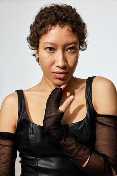Woman in black outfit poses in studio with unique expression