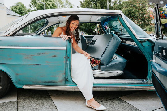 Bride stepping out of vintage car on wedding day