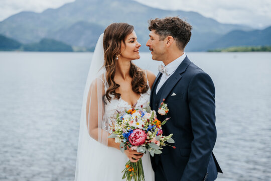 Bride and groom sharing intimate moment by alpine lake