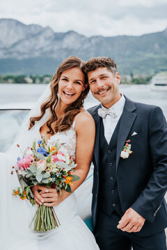Bride and groom holding bouquet at alpine lake wedding