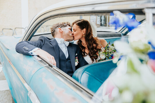 Bride and groom kissing in vintage car