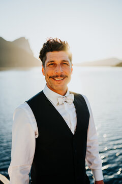 Confident man in smart attire standing by mountain lake at golde