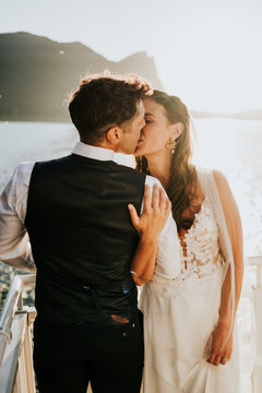 Close portrait of bride and groom kissing during lakeside weddin