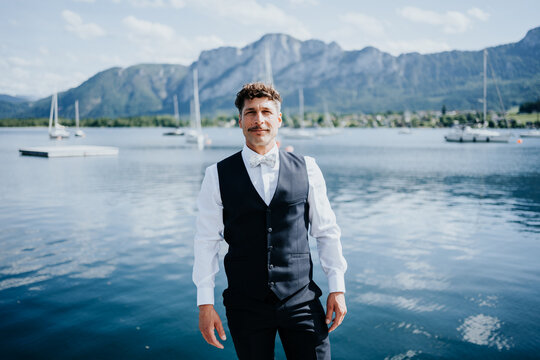 Groom portrait standing by Lake Mondsee before wedding celebrati