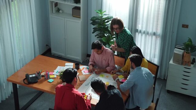 Close up of professional business team hands writing and putting sticky note on scrum task board. Top view of project manager write task and use kanban board to manage time and workflow. Convocation.
