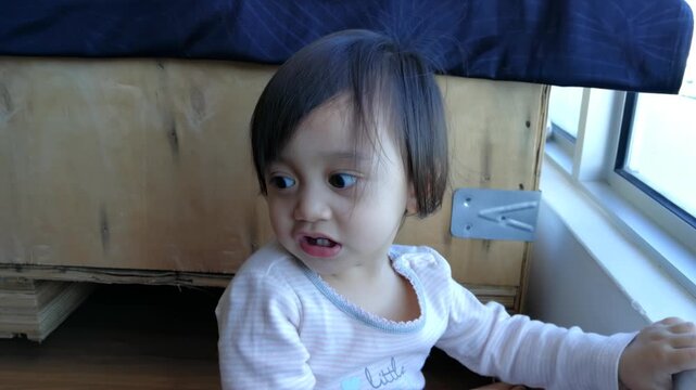 A talkative big-eyed toddler near apartment windows