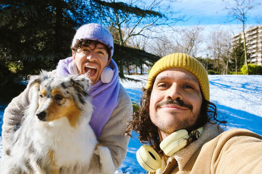 Two men taking selfie with dog in snowy park