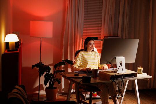 Woman working at home office desk at night