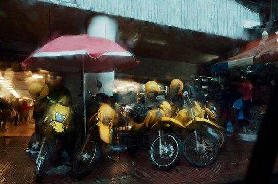 Yellow Motorcycles Parked Under Red Umbrella in the Rain