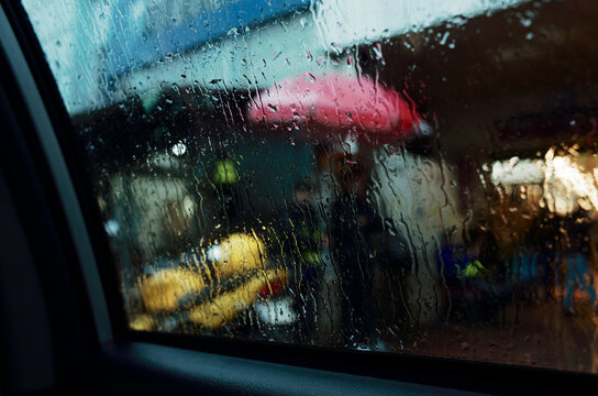 Raindrops on Window With People and Umbrellas in the Street